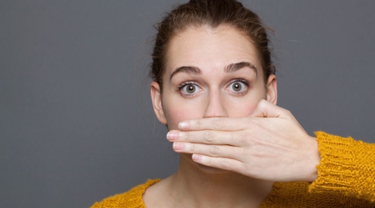 Woman covering her mouth as she has gum disease.